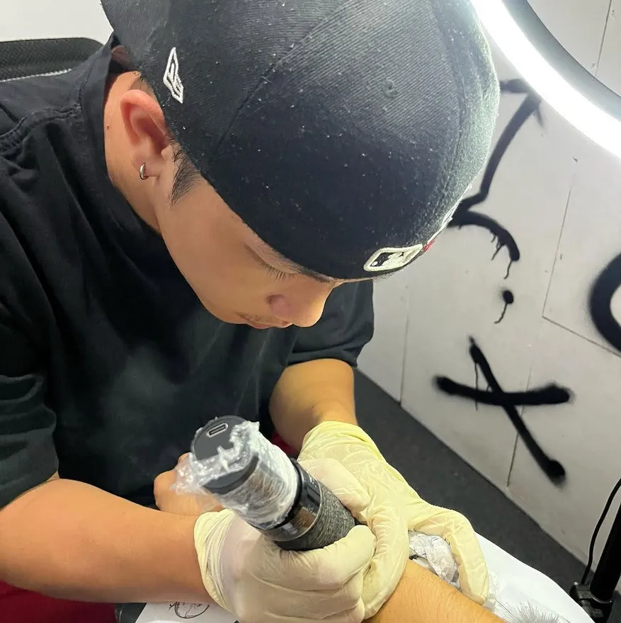 Carl Patrick Ando tattooing a client's arm