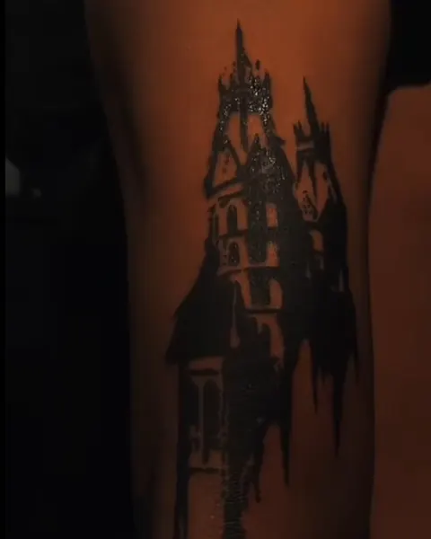 Blackwork tattoo of a gothic cathedral silhouette on an upper arm